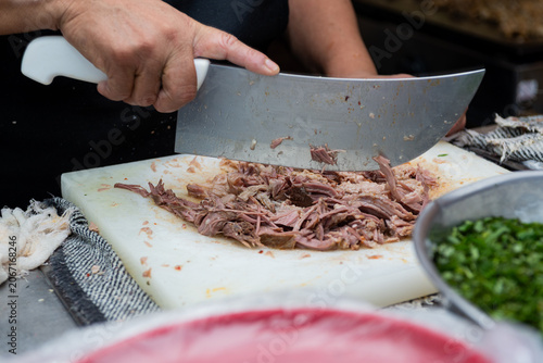 Female hands cutting meat at a taco stand. Mexican street food.