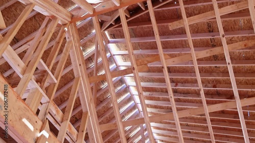 Workers construct roof with wooden frame beams trusses in building site