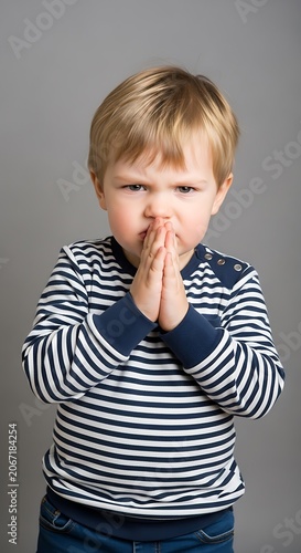 Cute toddler boy in striped shirt biting his lip.