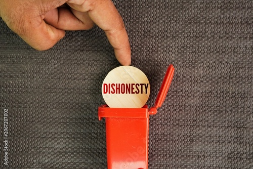 Fotografija Hand push or throw the word Dishonesty into the trash