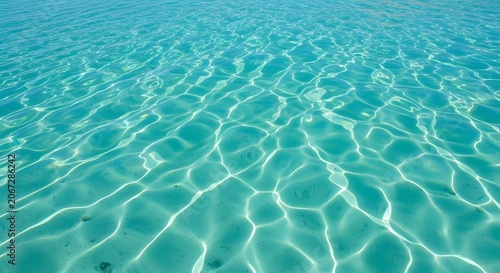 Crystal clear turquoise ocean water shimmers with bright sunlit ripples on a shallow sandy seafloor