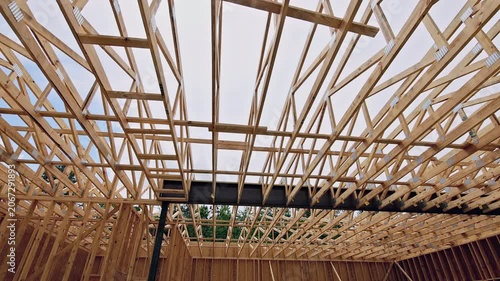Workers install wooden beams in house structure is with ongoing construction activity.