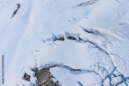 Bild auf Leinwand Aerial View of Glacier Crevasses and Snowfields Over Rocky Peaks in British Colu
