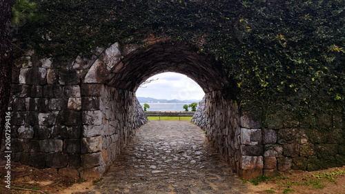 Bild auf Leinwand View to the Park and Sea through the Arc in Old Stone Wall