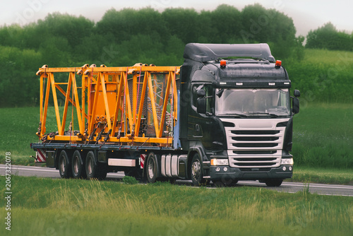 Transport vehicle carrying heavy equipment on countryside road