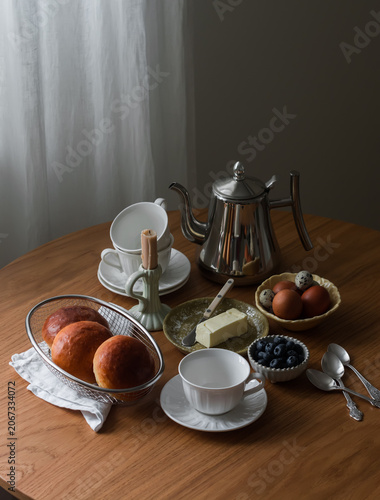 Homemade breakfast served on a wooden table - rolls, eggs, butter, coffee