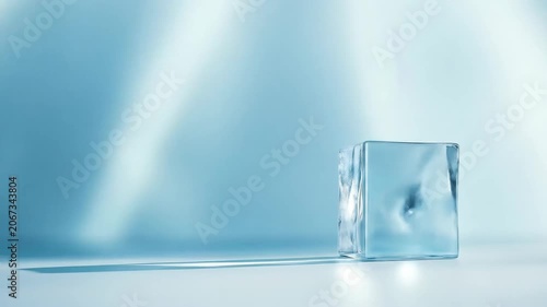 Transparent ice cube on blue backdrop with shadows and sunlight
