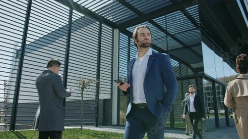 A man in a suit walks the city, on his phone and talking briefly