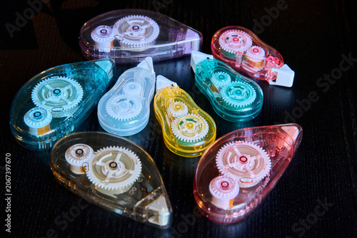 Obraz na płótnie A collection of colorful transparent correction tape dispensers with visible internal gear mechanisms on a dark table surface