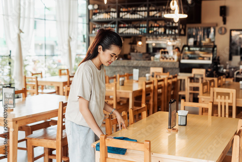 Valokuva A working student with a part-time job cleans a restaurant table while preparing for customers before opening hours