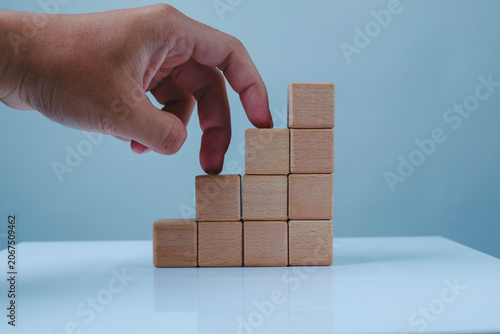 Konstfotografi Hand building a wooden block staircase on a light blue background, symbolizing business growth, strategic planning, career progress, goal achievement, and step-by-step development
