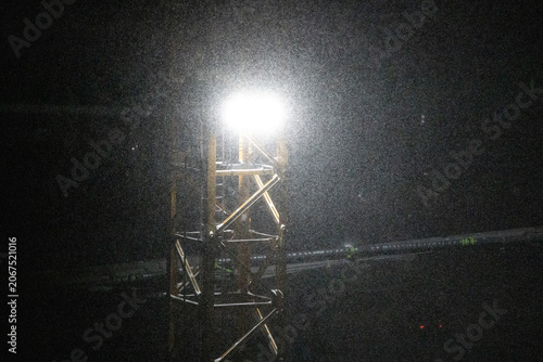 snow under the light of a construction crane at night