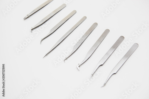 tools for eyelash extension and eyebrow design. cosmetic tweezers in silver color on a white background