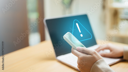 Photography Cybersecurity alert concept with warning notification on smartphone and laptop, representing cyber threats, fraud detection, and digital protection
