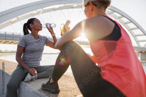 Fit women snacking and drinking water while taking a jogging break