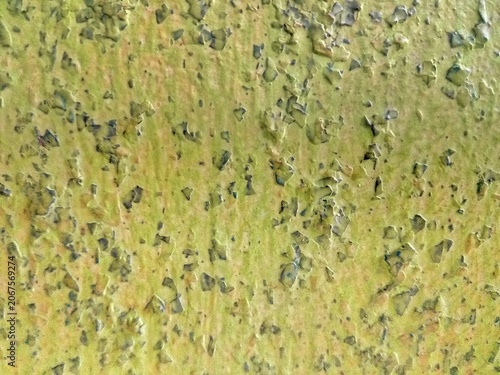 Close up of green painted wall texture with peeling paint and rough surface