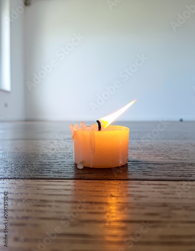 Small lit candle on wooden surface.