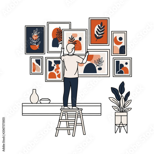 Man on stepladder hanging art gallery frames on living room wall with potted monstera plant.