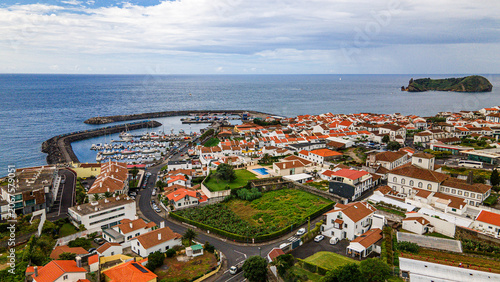 Coastal town overview with harbor marina waterfront and distant volcanic islet