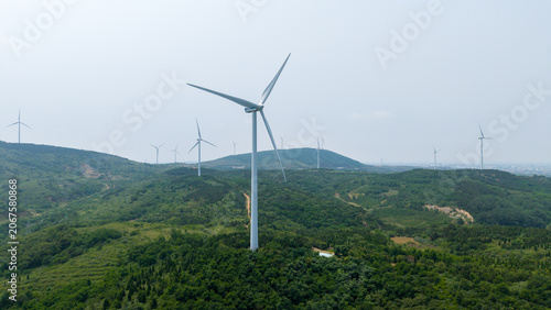 Wind turbines on green rolling hills under hazy sky