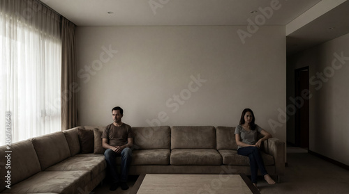 Couple experiencing emotional distance and relationship problems, sitting apart on a sofa in a silent living room