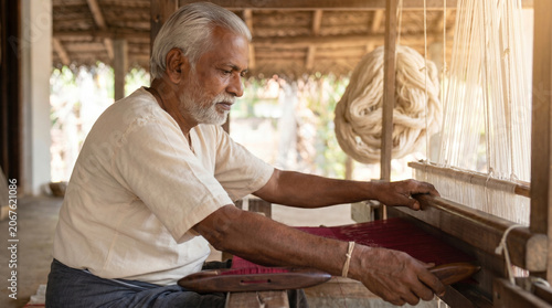 Indian weaver working on traditional loom - Elderly man weaving fabric on traditional loom in workshop  
