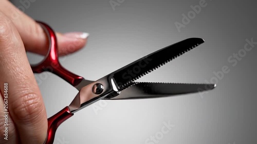 Hand holding sharp pinking shears against dark background.