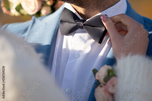 groom in a wedding suit with a bow tie. The bride's hands