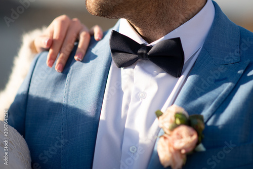 groom in a wedding suit with a bow tie. The bride's hands