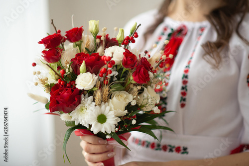 A bride holding a bouquet of pink and white roses in her hands.