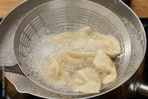 Bild auf Leinwand Boiling dumplings in metal strainer over pot