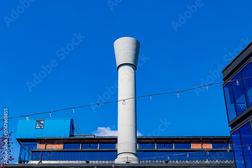 Foto Modern grey industrial chimney and string lights against a blue sky