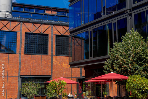 Quadro em tela Outdoor cafe with red umbrellas in a revitalized industrial brick courtyard