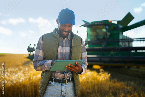 Tableau sur toile Farmer using a tablet in a wheat field to monitor farm operations and agricultural performance