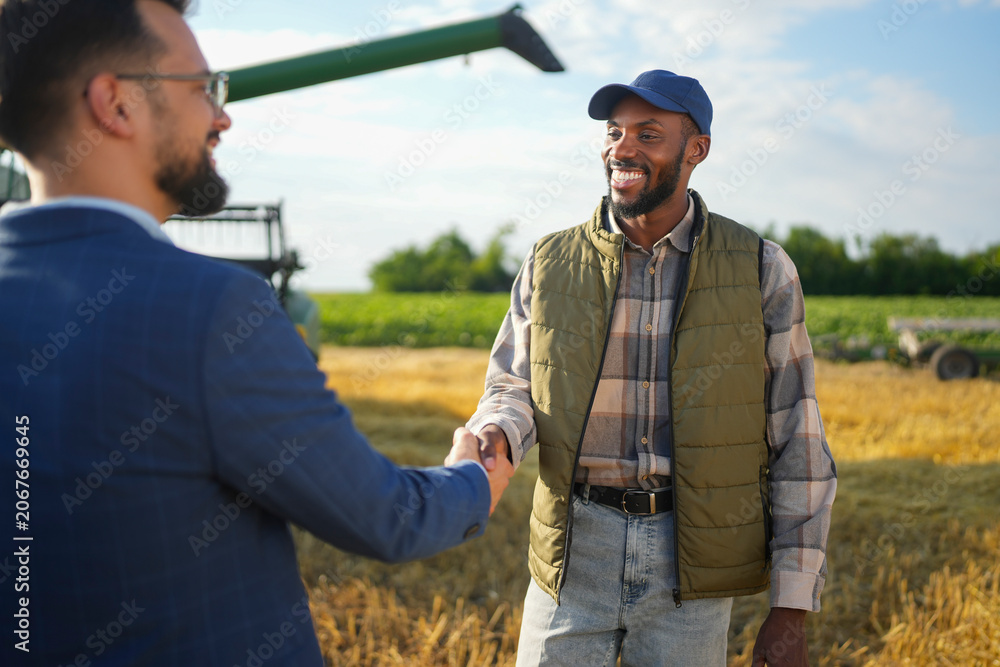 Fototapeta premium Farmer and agribusiness representative shaking hands after discussing agricultural cooperation and growth opportunities.