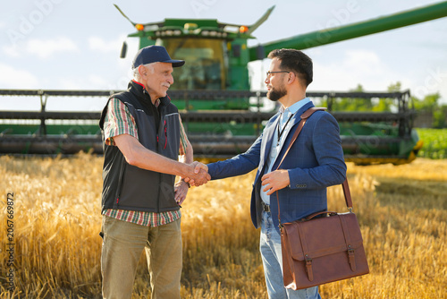 Fotografie Farmer and agribusiness professional shaking hands after a successful business discussion