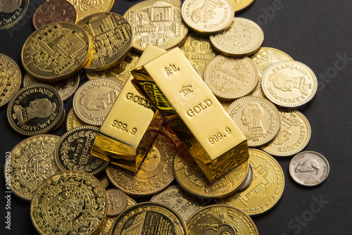 Fotografie Gold bars on assorted coins representing wealth and investment