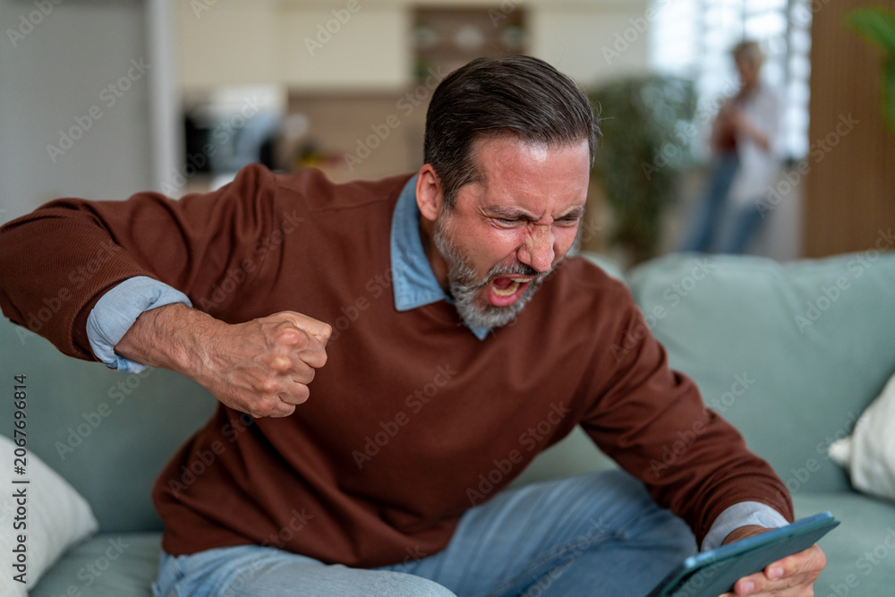 Fototapeta premium Angry man yelling, screaming in frustration at tablet
