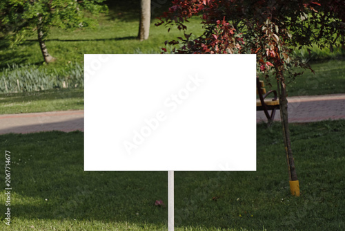 Canvas Print Empty rectangular billboard on a pole in parkland with trees and grass, providin