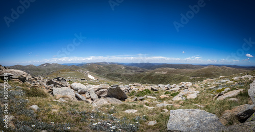 Panorama view from top of Mount Kosciuszko during a clear day, showcasing vast alpine landscapes and rugged terrain, Australia