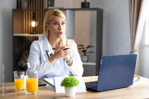 Obraz na plátně Female doctor in white coat talking, offering telemedicine assistance and profes