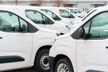 White delivery vans are parked in rows. Commercial fleet of vehicles