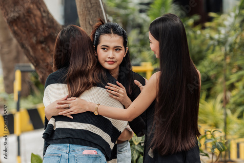 Obraz na plátně A young Southeast Asian woman hugs her friend while showing a treacherous smile, creating mixed emotions of affection, secrecy, and hidden intentions