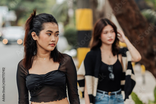 Bild auf Leinwand A young Southeast Asian woman looks back at another woman with envy, showing jealousy, comparison, and hidden emotional tension