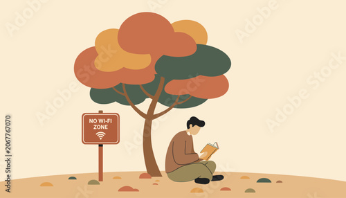Young man enjoying a quiet moment reading a book under a colorful autumn tree in a designated no wi-fi zone area.