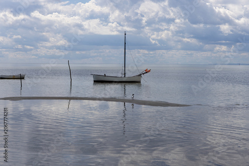 Lonely boat anchored in calm Baltic Sea under dramatic cloudy sky in Hel Peninsula, Poland