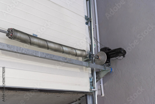 Steel torsion spring balancing mechanism on white sectional garage door