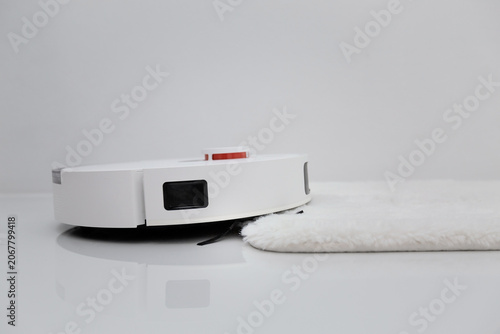 White robotic vacuum cleaner on ceramic floor cleaning