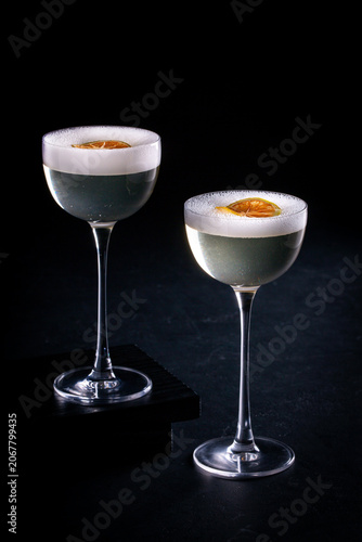 Two elegant cocktail glasses with citrus garnish on dark background