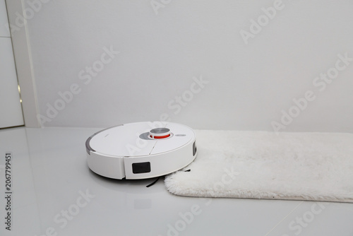 White robotic vacuum cleaner on ceramic floor cleaning